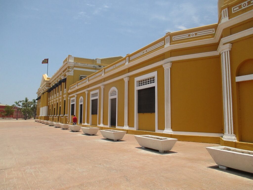 A daytime image of the ochre-colored Plaza de la Aduana building in Barrio Abajo, Barranquilla, Colombia, photo ©Kate Dana
