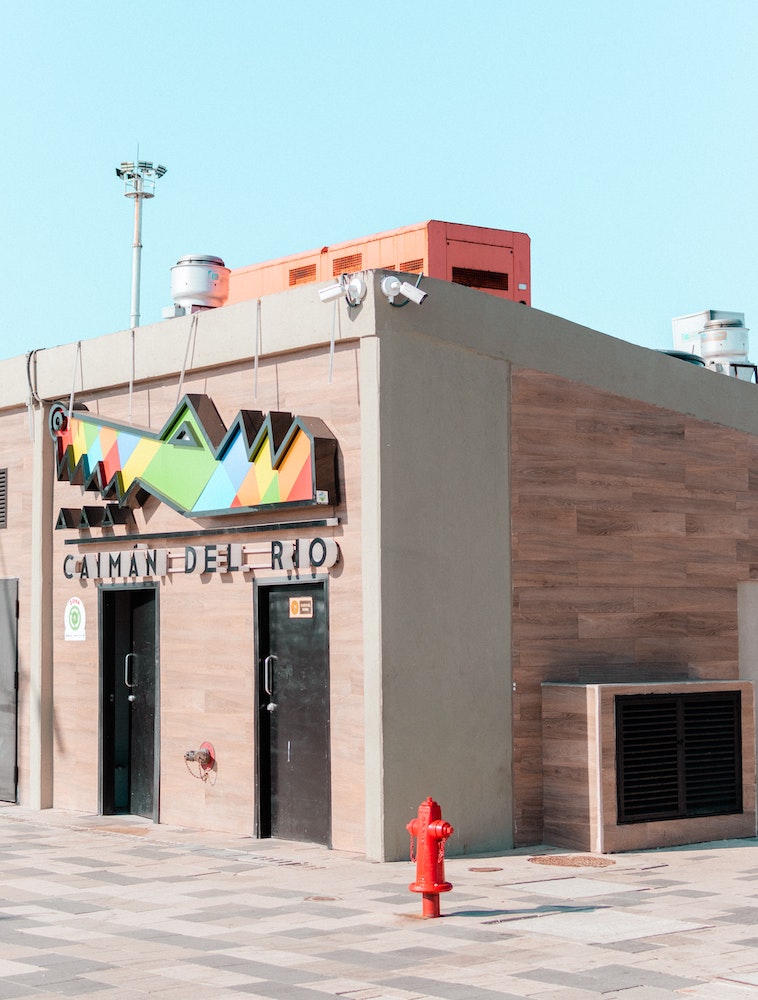 A colorful sign on a building outdoors announces the Caiman del Rio establishment for Malecón visitors in Barranquilla, Colombia photo ©Kevin Kleber for pexels.com