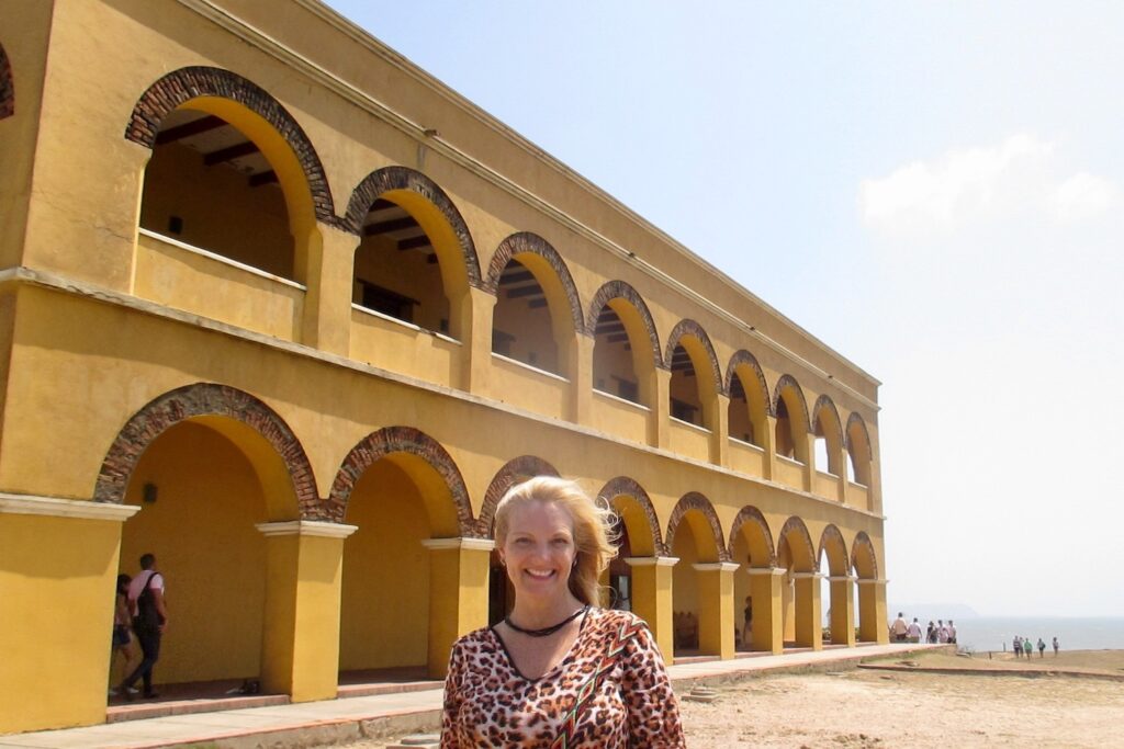 Travel blogger Kate Dana stands outside of ochre-colored Castillo Salgar in Barranquilla, Colombia, photo ©Kate Dana