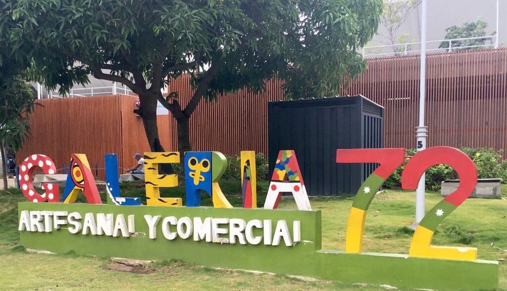 A colorful lettered sign in the grass announces the location of Galeria Artesanal & Comercial 72 in Barranquilla, Colombia, photo ©Kate Dana