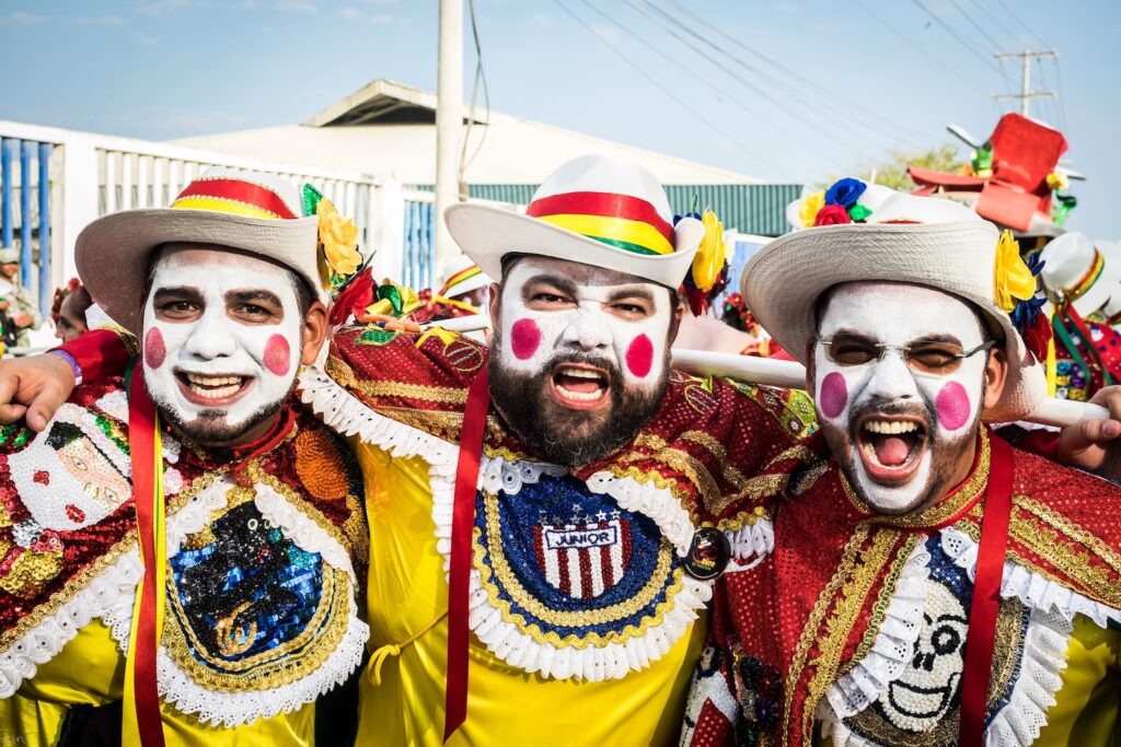 3 Gozaderos (party-goers) with face paint and brilliant costumes during the Carnaval in Barranquilla, Colombia, photo ©Hernan Pernett for Pexels.com