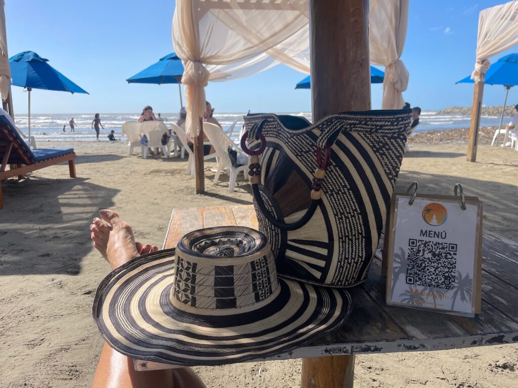 A handcrafted caña flecha bag and sombrero vueltiao rest on a seaside table at Kilymandiaro Sunset Paradise in Barranquilla, Colombia photo ©Kate Dana
